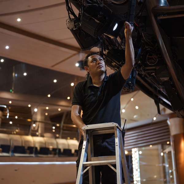 Lighting technician adjusting a stage light above a cruise ship theatre