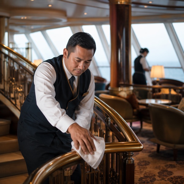 Public area cleaner polishing a railing in a cruise ship lounge