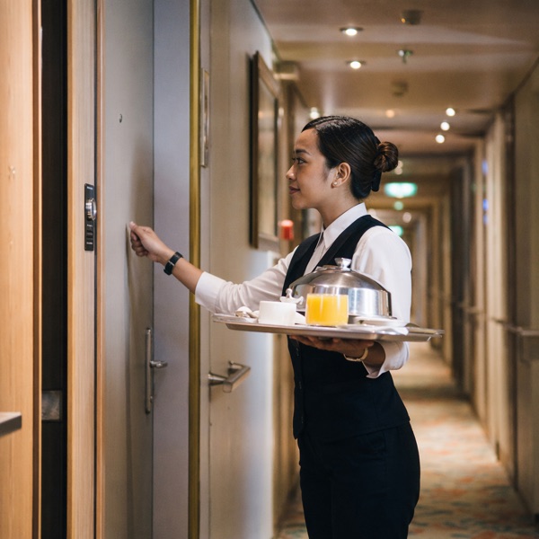 Room service attendant delivering a tray to a stateroom door
